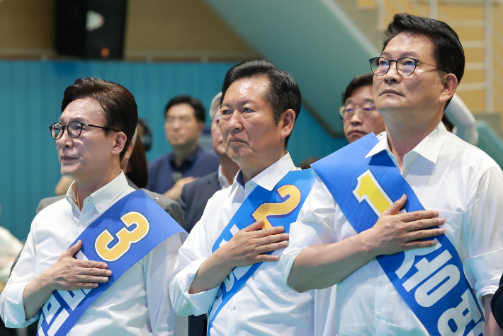 더불어민주당 김민석· 정청래·송영길 당 대표 후보가 9일 강원도 횡성국민체육센터에서 열린 민주당 대표·최고위원 후보자 강원 합동연설회에서 국기에 경례하고 있다. 연합뉴스