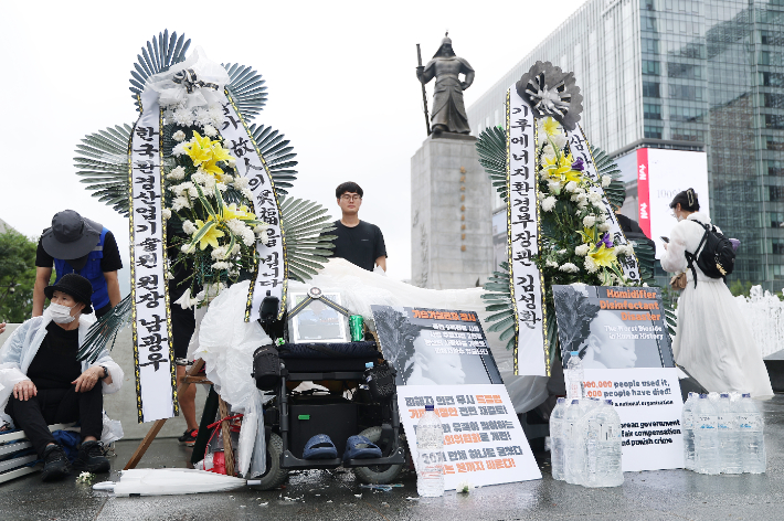 16일 서울 종로구 광화문광장에 전국가습기살균제참사피해자연대가 설치한 조화와 손팻말이 놓여 있다. 연합뉴스
