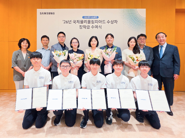 전영현 삼성전자 DS 부문장(부회장, 뒷줄 오른쪽)과 윤진희 한국물리학회장(뒷줄 왼쪽), 올해 국제물리올림피아드 수상자들(앞줄 전원)과 학부모 등이 지난 13일 삼성전자 화성캠퍼스에서 열린 장학금 수여식에 참석해 기념촬영하고 있다. 삼성 제공