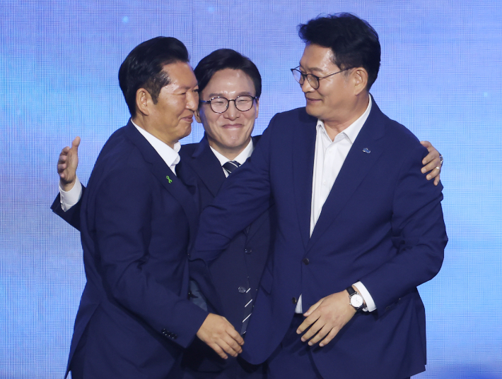 더불어민주당 당 대표에 출마한 김민석 전 총리가 17일 대전 컨벤션센터에서 열린 제3회 더불어민주당 정기 전국당원대회에서 당 대표 당선을 확정한 뒤 본선에서 경쟁을 벌였던 정청래 전 대표, 송영길 의원과 포옹하고 있다. 연합뉴스