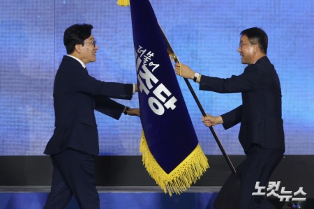 17일 대전 유성구 대전컨벤션센터 제2전시장에서 열린 더불어민주당 제3차 정기전국당원대회에서 선출된 김민석 당대표가 한병도 원내대표로부터 당기를 전달받고 있다.