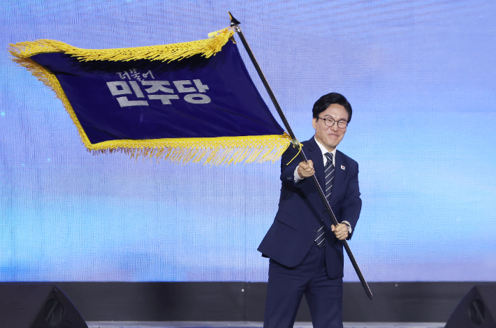 더불어민주당 당 대표에 출마한 김민석 전 총리가 17일 대전 컨벤션센터에서 열린 제3회 더불어민주당 정기 전국당원대회에서 당 대표 당선을 확정한 뒤 당기를 흔들고 있다. 연합뉴스