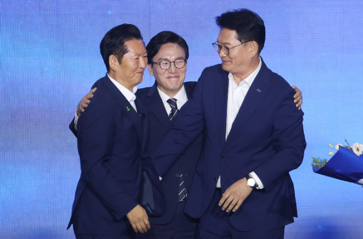 더불어민주당 당 대표에 출마한 김민석 전 총리가 17일 대전 컨벤션센터에서 열린 제3회 더불어민주당 정기 전국당원대회에서 당 대표 당선을 확정한 뒤 본선에서 경쟁을 벌였던 정청래 전 대표, 송영길 의원과 포옹하고 있다. 연합뉴스