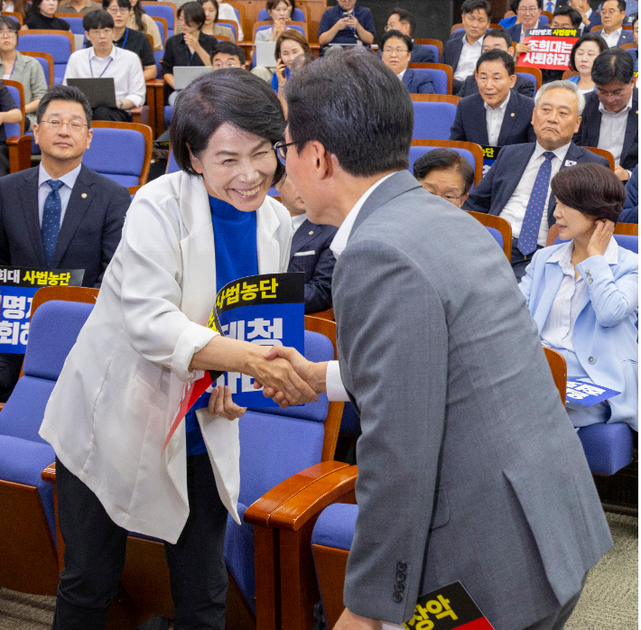 더불어민주당 최민희 최고위원(왼쪽)이 20일 국회에서 전당대회 뒤 처음으로 열린 의원 총회에서 김민석 대표와 악수하고 있다. 연합뉴스