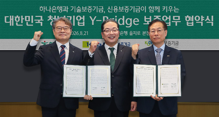 하나은행은 청년사업가의 도전과 성장을 지원하고, 글로벌 경쟁력을 갖춘 청년기업 육성을 위해 기술보증기금, 신용보증기금과 「청년기업 도약을 위한 Y-BRIDGE 보증 금융지원」 업무협약을 체결했다. 지난 21일 서울시 중구 하나은행 을지로 본점에서 개최된 협약식에서 이호성 하나은행장(사진 가운데)이 권형택 기술보증기금 이사장(사진 오른쪽), 강승준 신용보증기금 이사장(사진 왼쪽)과 함께 협약서를 들고 기념촬영을 하고 있다. 하나은행 제공 