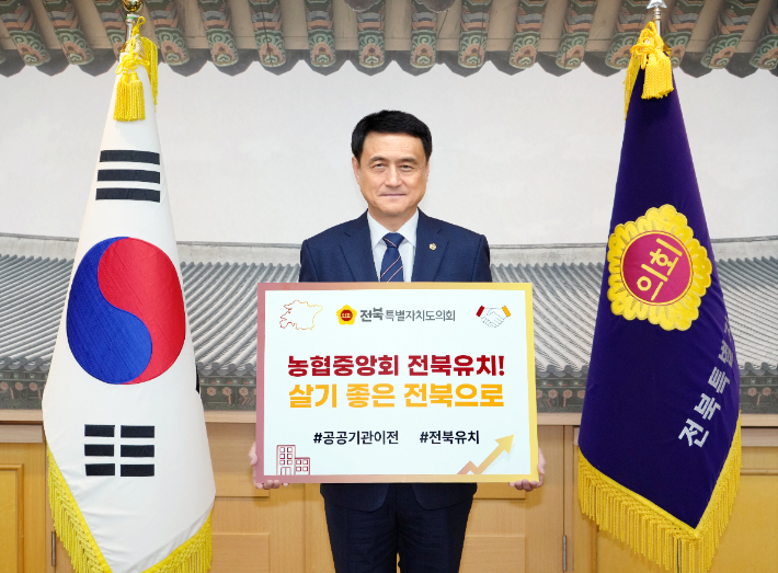 김희수 전북도의회 의장이 25일 농협중앙회 전북 이전을 촉구하는 손팻말을 들고 있다. 전북도의회 제공