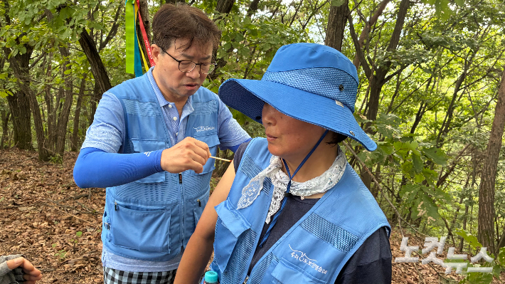 우리강 도보순례를 하던 중 벌에 쏘인 참가자를 치료해주는 순례단장인 더불어민주당 염태영 의원(사진 왼쪽). 김수진 기자