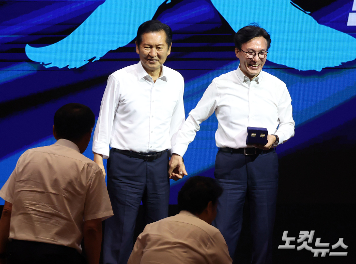 더불어민주당 김민석 대표가 정청래 전 대표에게 감사패 전달 전 손을 맞잡고 있다. 인천=황진환 기자