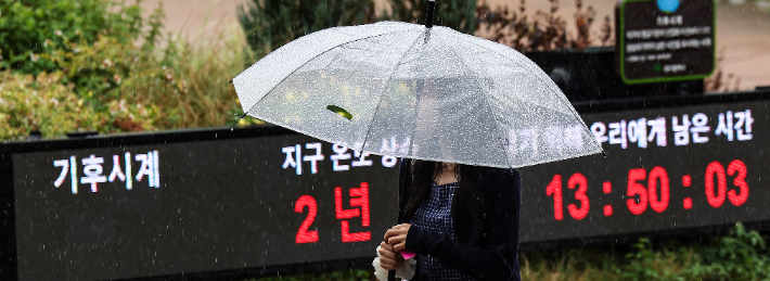 28일 동대구역 광장에 설치된 기후시계 앞으로 시민이 우산을 쓰고 이동하고 있다. 연합뉴스