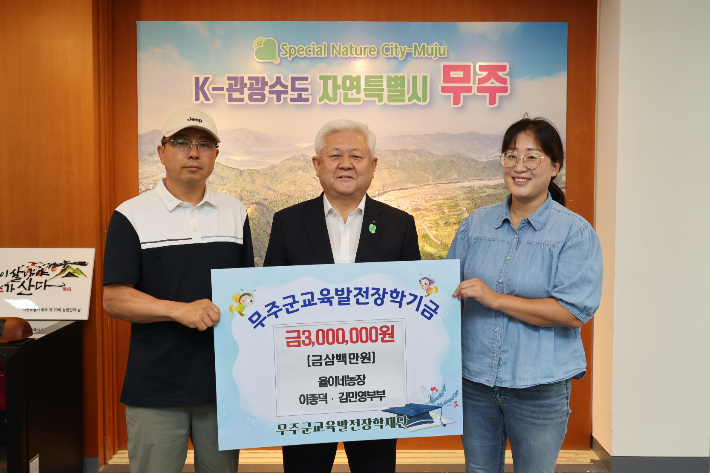 무주에서 율이네 농장을 운영하는 이종덕·김민영 부부가 31일 황인홍 무주군수(가운데)에게 교육발전장학기금 300만원을 맡겼다. 무주군 제공