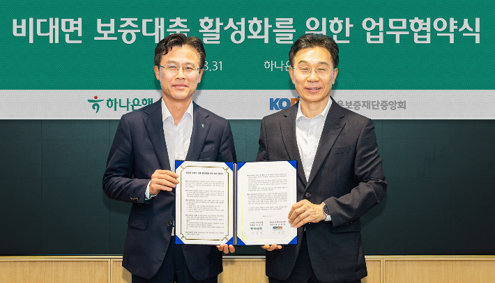 하나은행은 지난달 31일 오후 하나은행 을지로 본점에서 '비대면 보증부 대출 활성화를 위한 업무협약'을 체결했다. 이날 협약식에 참석한 서유석 하나은행 기업그룹 부행장(사진 왼쪽)이 이상천 신용보증재단중앙회 전무이사(사진 오른쪽)와 함께 협약서를 들고 기념촬영을 하고 있다. 하나은행 제공 