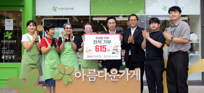 BNK경남은행 이명훈 부장(사진 오른쪽 네번째)이 아름다운가게 경남본부 정윤희 본부장에게 헌책을 전달한 뒤 단체 기념촬영을 하고 있다. BNK경남은행 제공 