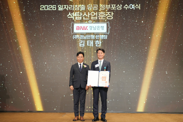 BNK경남은행 김태한 은행장(사진 오른쪽)이 고용노동부 김영훈 장관으로부터 석탑산업훈장을 받고 있다. BNK경남은행 제공 