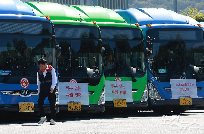 통상임금 적용과 임금 인상을 놓고 대립 중인 서울 시내버스 노사가 노조의 파업 예고일을 하루 앞둔 15일 서울 시내 한 공영차고지에 '파업 반대' 현수막이 걸린 버스들 앞으로 투쟁 머리띠를 목에 두른 노조원이 발걸음을 옮기고 있다.  노조는 이날 2차 조정 회의를 가진 후 결렬되면 16일 첫차부터 전면 파업에 나선다. 류영주 기자