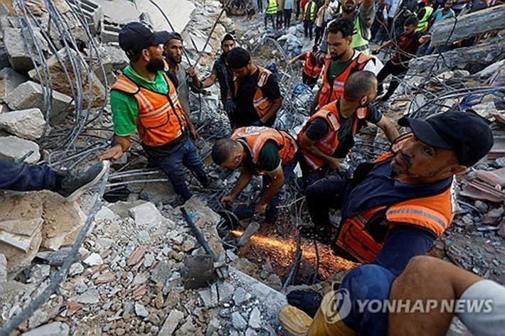 16일 가자시티에서 구조대원들이 무너져 내린 주거용 건물 잔해 속에서 팔레스타인 희생자의 시신을 수습하고 있다. 로이터/연합뉴스