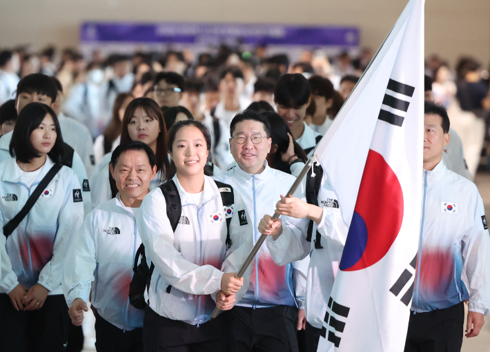 2026 아이치·나고야아시안게임 탁구 국가대표 신유빈이 17일 선수단 본진 기수로 태극기를 들고 이상현 단장 등과 출국하고 있다. 연합뉴스 