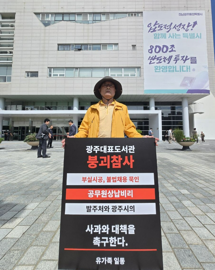 17일 전남광주통합특별시청 앞에서 광주대표도서관 붕괴참사 유가족이 부실시공과 불법채용 묵인, 공무원 상납비리 등에 대한 사과와 대책 마련을 촉구하는 피켓을 들고 있다. 유가족 측 제공
