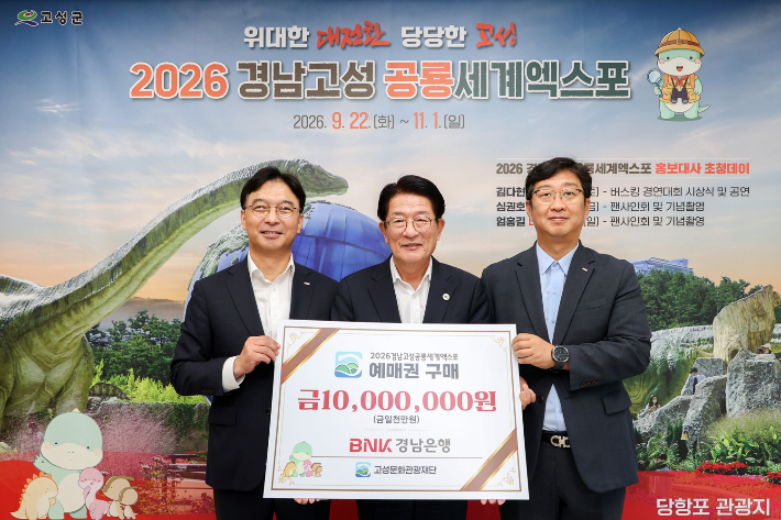 BNK경남은행 임재문 그룹장(사진 왼쪽 첫번째)이 고성군 하학열 군수(가운데)에게 '2026경남고성공룡세계엑스포 예매권 구매 증서'를 전달한 뒤 기념촬영을 하고 있다. BNK경남은행 제공 