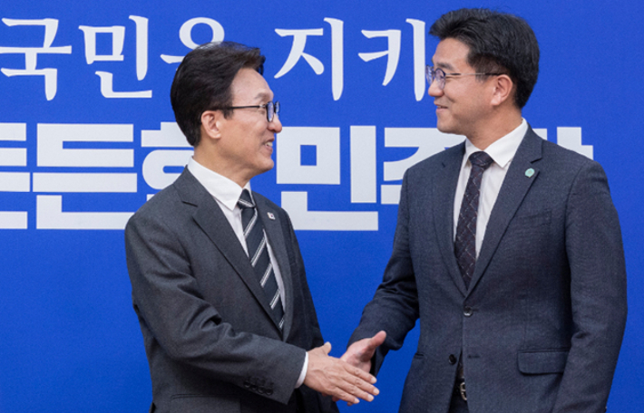 더불어민주당 김민석 대표(왼쪽)가 21일 국회에서 취임 인사차 방문한 기본소득당 오준호 대표를 만나 악수하고 있다. 연합뉴스