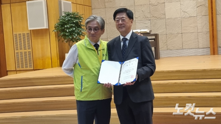 서울연회 감독 당선자 최우성 목사(오른쪽)가 교부 받은 당선증을 들고 연회 선관위원장과 기념 촬영하고 있다.