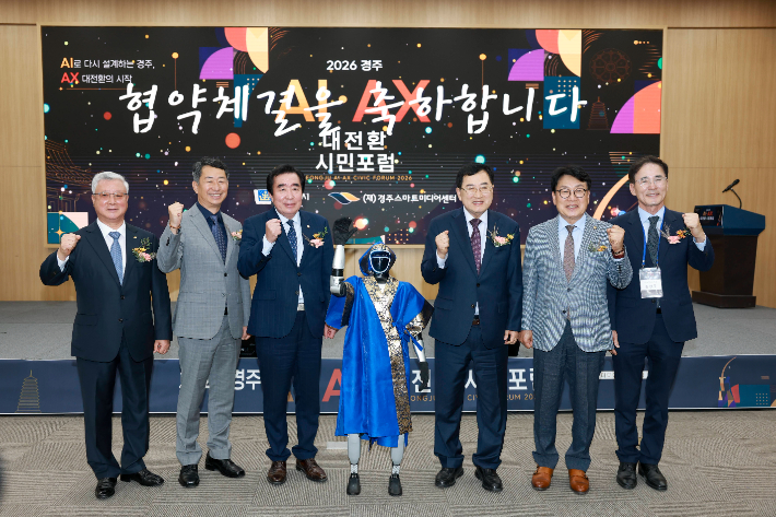 주낙영 경주시장과 임활 경주시의회 의장을 비롯한 참석자들이 '2026 경주 AI·AX 대전환 시민포럼'에서 휴머노이드 로봇과 함께 기념촬영을 하고 있다. 경주시 제공