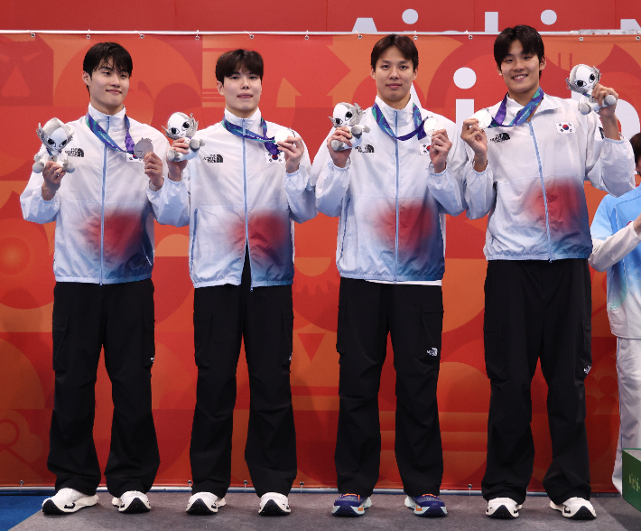 지난 24일 도쿄 아쿠아틱스 센터에서 열린 2026 아이치·나고야 아시안게임 수영 남자 400m 자유형 계영 결승에서 은메달을 따낸 대한민국 선수들이 메달을 목에 걸고 기뻐하고 있다. 연합뉴스