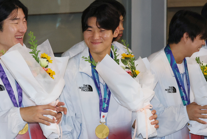2026 아이치·나고야 아시안게임에서 우승을 차지한 한국 야구 대표팀 김도영(가운데)이 곽빈 등 선수들과 28일 인천국제공항을 통해 귀국해 꽃다발을 받고 활짝 웃고 있다. 연합뉴스 