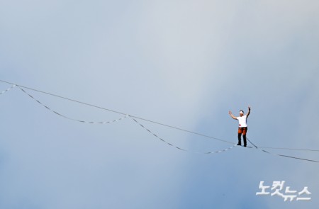 에스토니아 출신 슬랙라인 선수 얀 루스(Jaan Roose)가 1일 서울 광화문 도심 120m 상공에서 '레드불 서울 줄타기' 퍼포먼스를 선보이고 있다. 슬랙라인은 두 지점 사이를 이어 팽팽하게 설치한 폭 2.5~5cm 안팎의 줄 위에서 균형을 잡아 걷거나 점프, 회전 등의 기술을 선보이는 스포츠로, 이날 얀 루스는 코리아나호텔을 출발해 동아미디어센터를 반환점으로 돌아오는 편도 160m 구간의 고공 왕복 횡단에 도전했다.