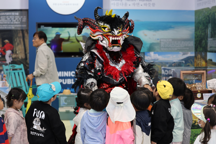 여수세계섬박람회를 찾은 아이들이 도미니카공화국의 전통 축제 의상 '디아블로 코후엘로'를 입은 캐릭터를 구경하고 있다. 여수세계섬박람회 조직위 제공