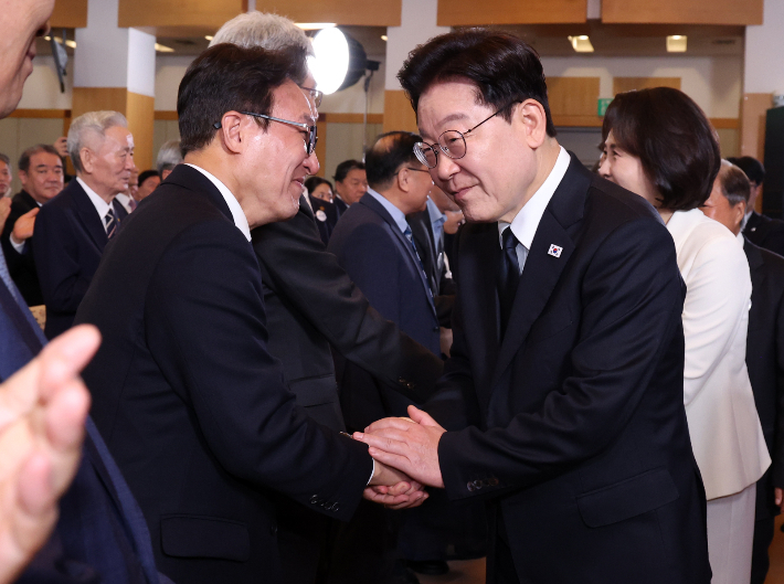 이재명 대통령이 16일 부산시청에서 열린 부마민주항쟁 47주년 기념식에 입장하며 더불어민주당 김민석 대표와 인사하고 있다. 연합뉴스