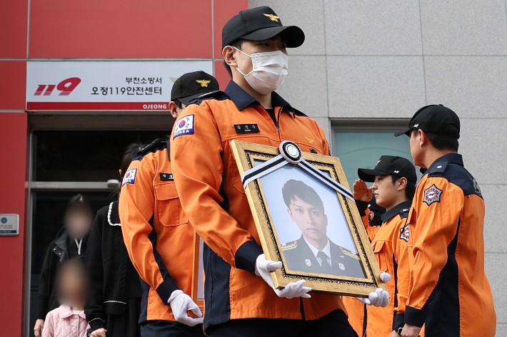 19일 고(故) 김진석 소방위 영결식이 끝난 뒤 동료 소방관들이 영정과 위패를 들고 고인의 생전 근무지인 경기도 부천소방서 오정119안전센터를 돌아본 뒤 건물을 나서고 있다. 연합뉴스