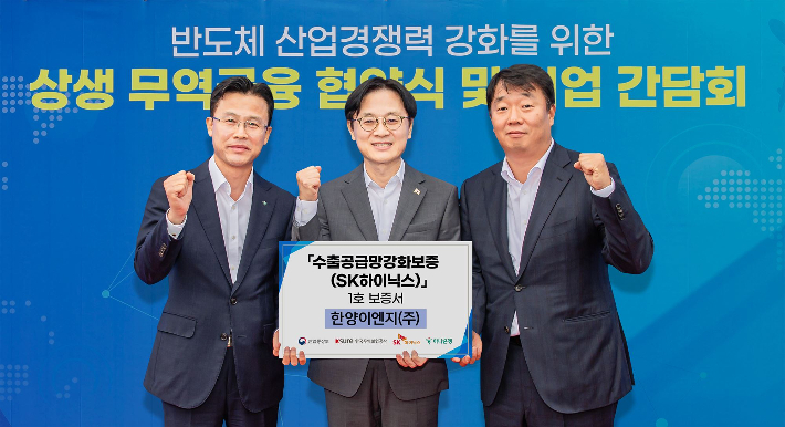 하나은행은 지난 19일 SK하이닉스, 한국무역보험공사 및 KB국민은행ㆍ신한은행ㆍ우리은행과 함께 반도체 산업 수출공급망 강화금융 업무협약을 체결했다.이날 협약식에서 김정관 산업통상부 장관(사진 가운데)과 서유석 하나은행 기업그룹 부행장(사진 왼쪽)이 SK하이닉스 협력기업인 한양이엔지(주)에 1호 보증서를 전달하며 기념촬영을 하고 있다. 하나은행 제공 