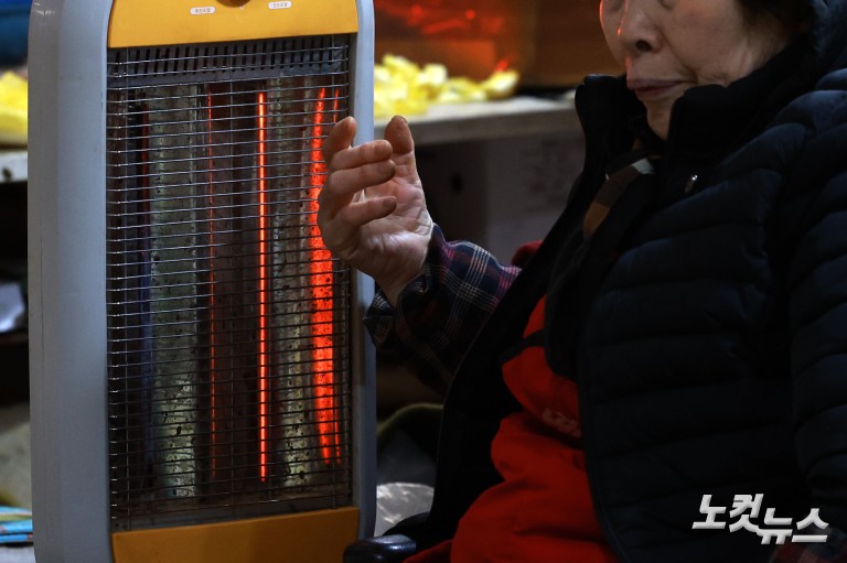 난로 쬐며 추위 녹이는 시장 상인들